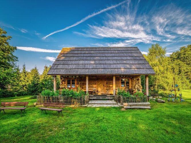 a log cabin with two benches in the grass at Holiday Home in Be czna near Lake Kl pnicko in Bełzcna