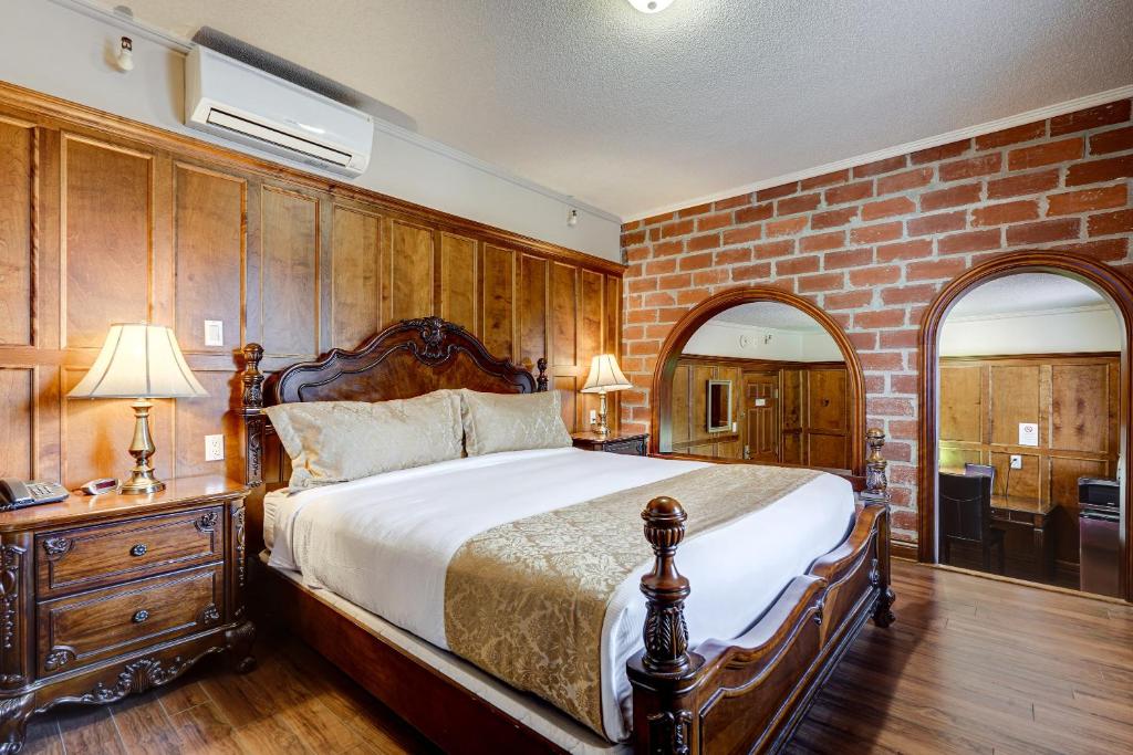 een slaapkamer met een groot bed en een bakstenen muur bij Le Grand Hôtel in Baie-Comeau