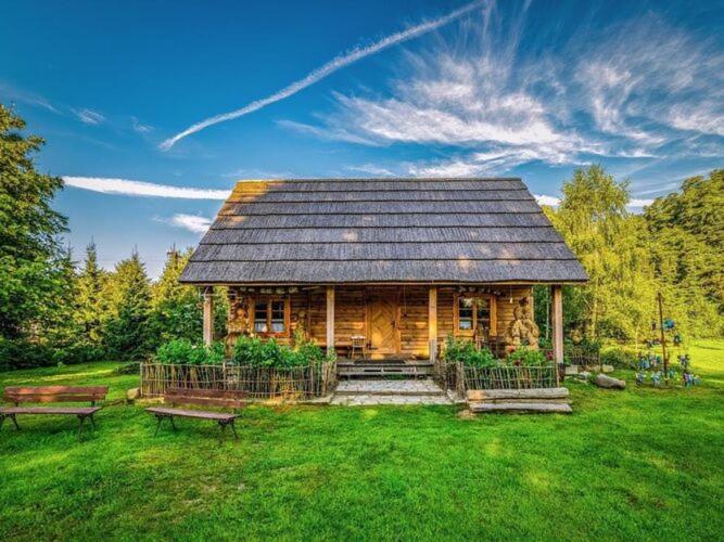 une cabane en rondins avec deux bancs dans l'herbe dans l'établissement Comfortable holiday home in the countryside, Be czna, 