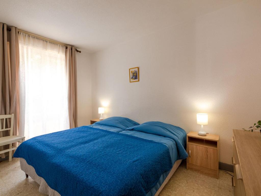 a bedroom with a blue bed and a window at Apartment Le Grand Large-1 by Interhome in Sainte-Maxime