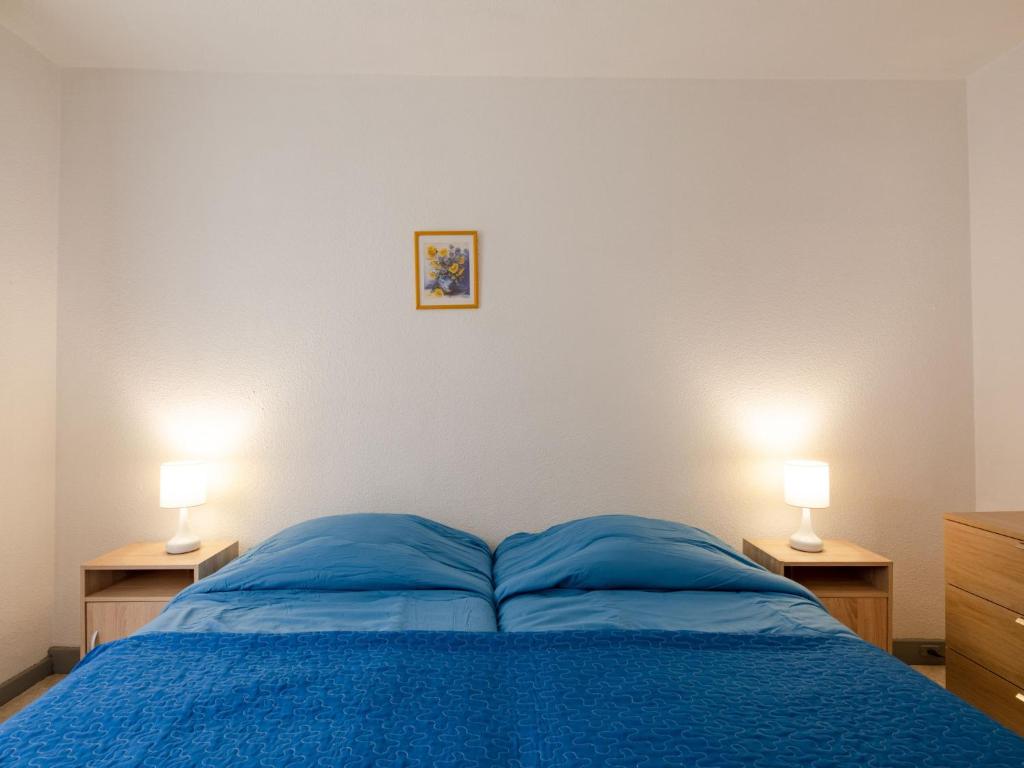 a bedroom with a bed with blue sheets and two lamps at Apartment Le Grand Large-1 by Interhome in Sainte-Maxime