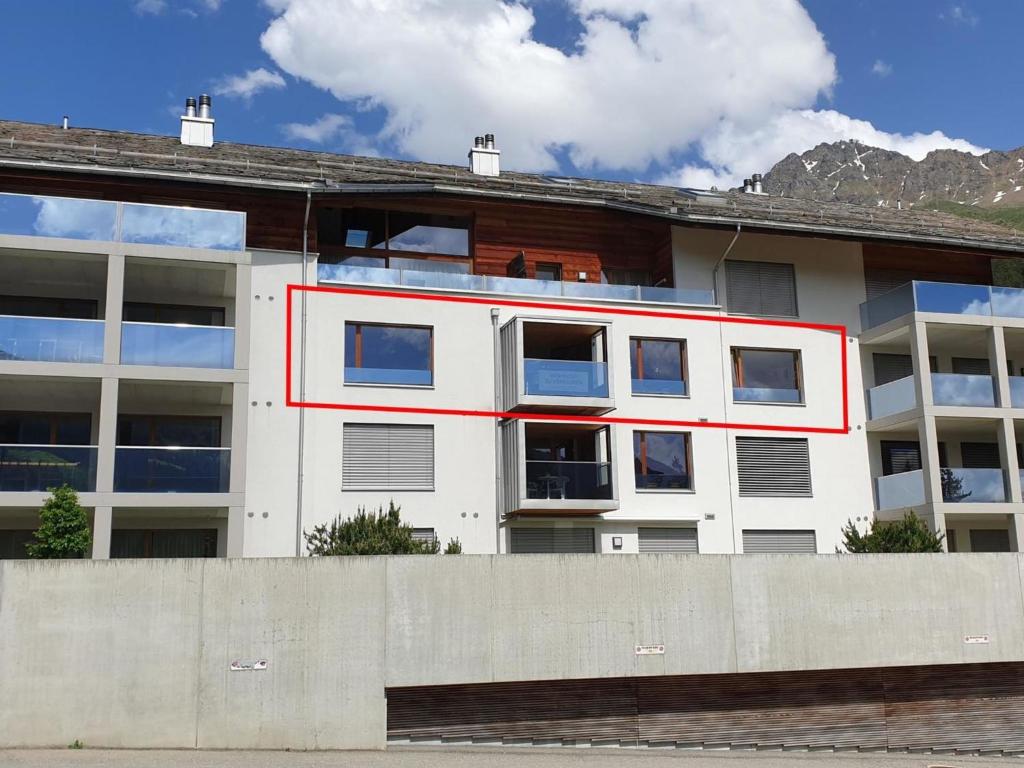 un edificio blanco con una raya roja. en Apartment Uehlinger Züger by Interhome en Valbella