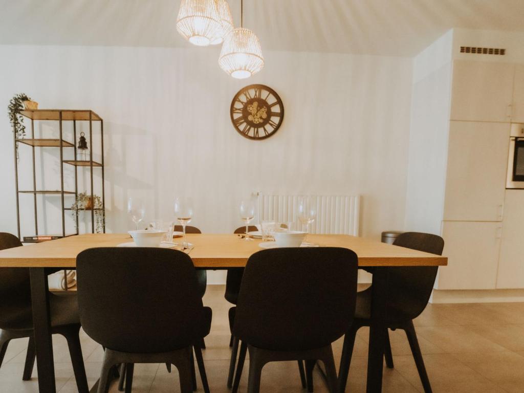 a dining room table with chairs and a clock on the wall at Apartment Rodenbach by Interhome in De Haan