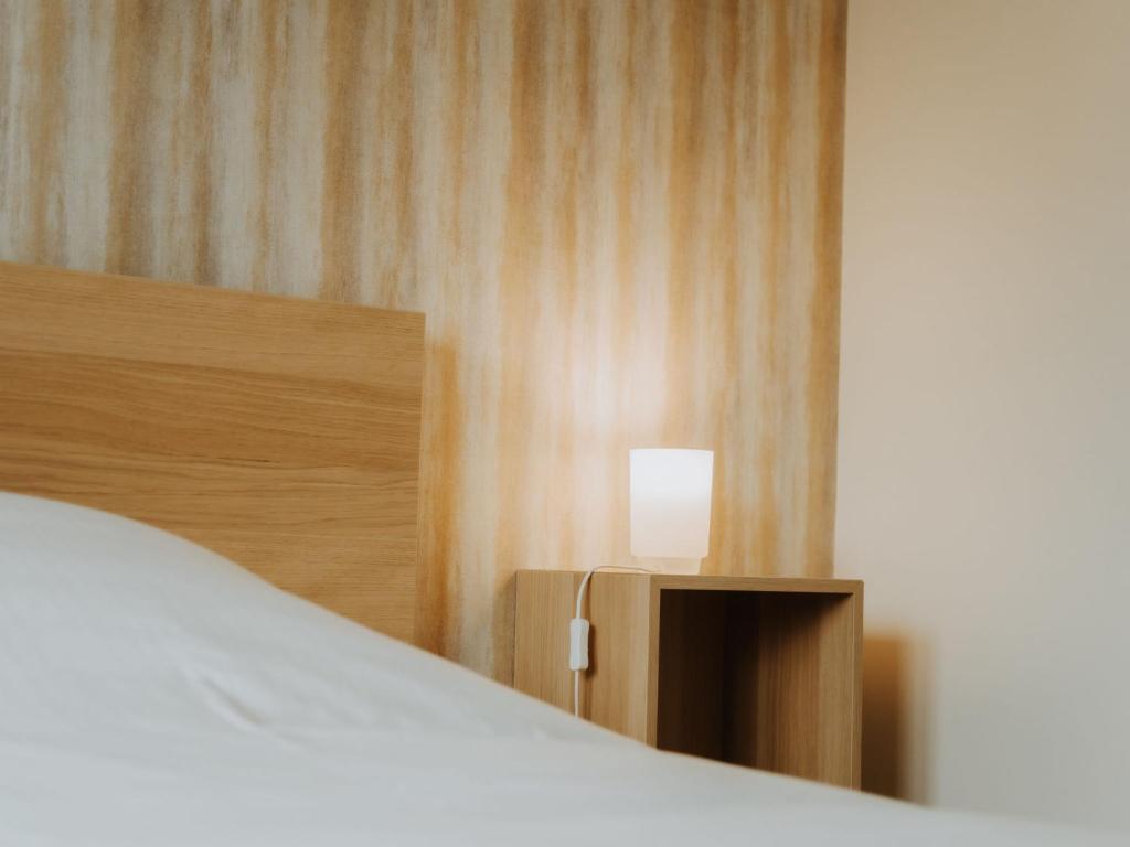 a bedroom with a bed and a lamp on a wall at Apartment Rodenbach by Interhome in De Haan