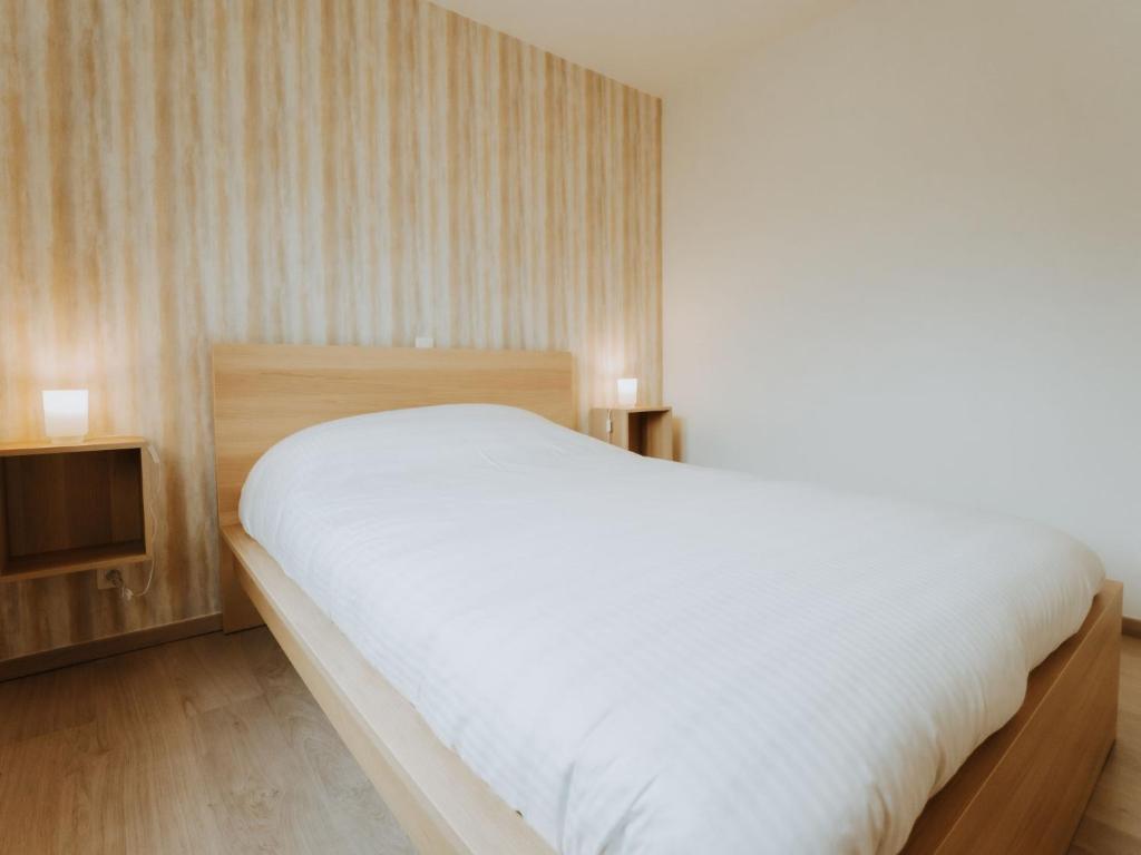 a bedroom with a large white bed and wooden floors at Apartment Rodenbach by Interhome in De Haan