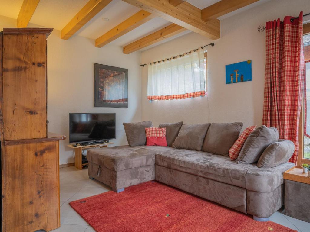 een woonkamer met een bank en een flatscreen-tv bij Chalet Le Coprin by Interhome in Ovronnaz