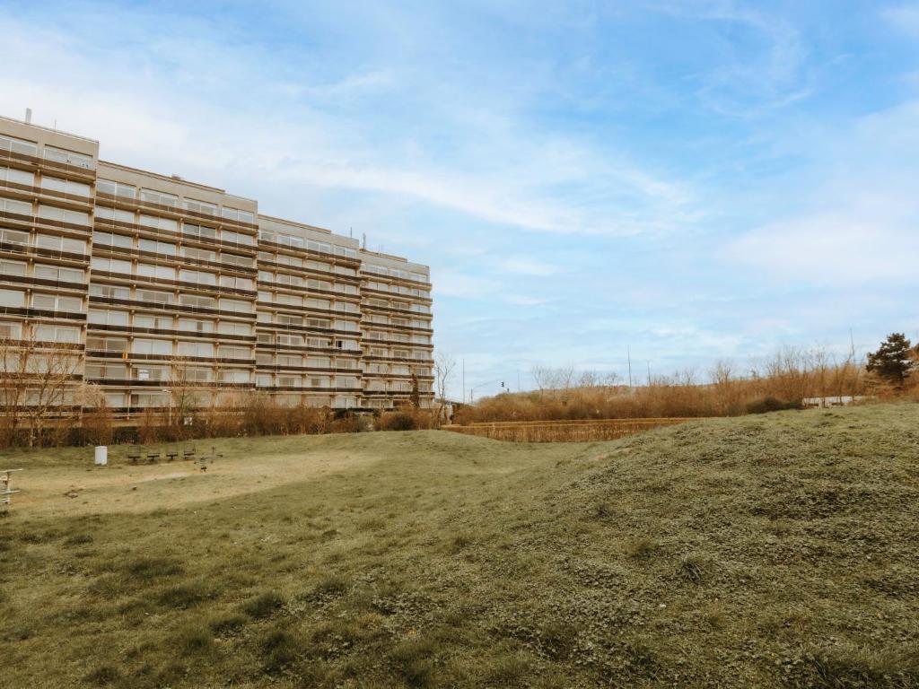 an empty field in front of a large building at Studio Zeeduin by Interhome in Bredene