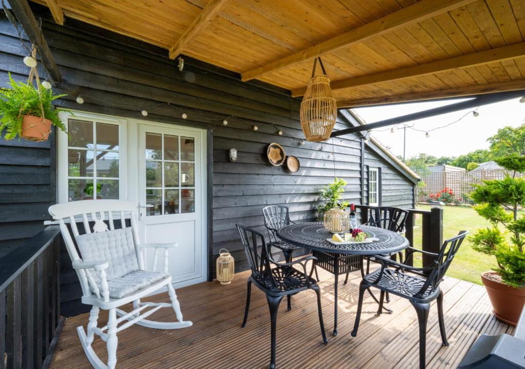 eine Terrasse mit einem Tisch und Stühlen auf einer Terrasse in der Unterkunft Oak Barn Annexe in Trimley Heath