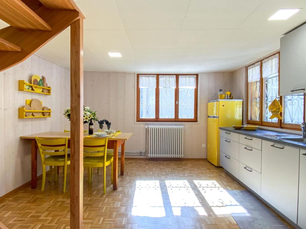 una cucina con tavolo e frigorifero giallo di Apartment Casa della Posta-1 by Interhome a Rossa