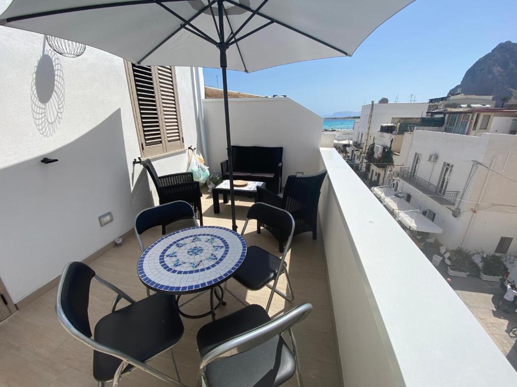 un tavolo e sedie su un balcone con ombrellone di Ca Sà Bellò San Vito Lo Capo a San Vito lo Capo