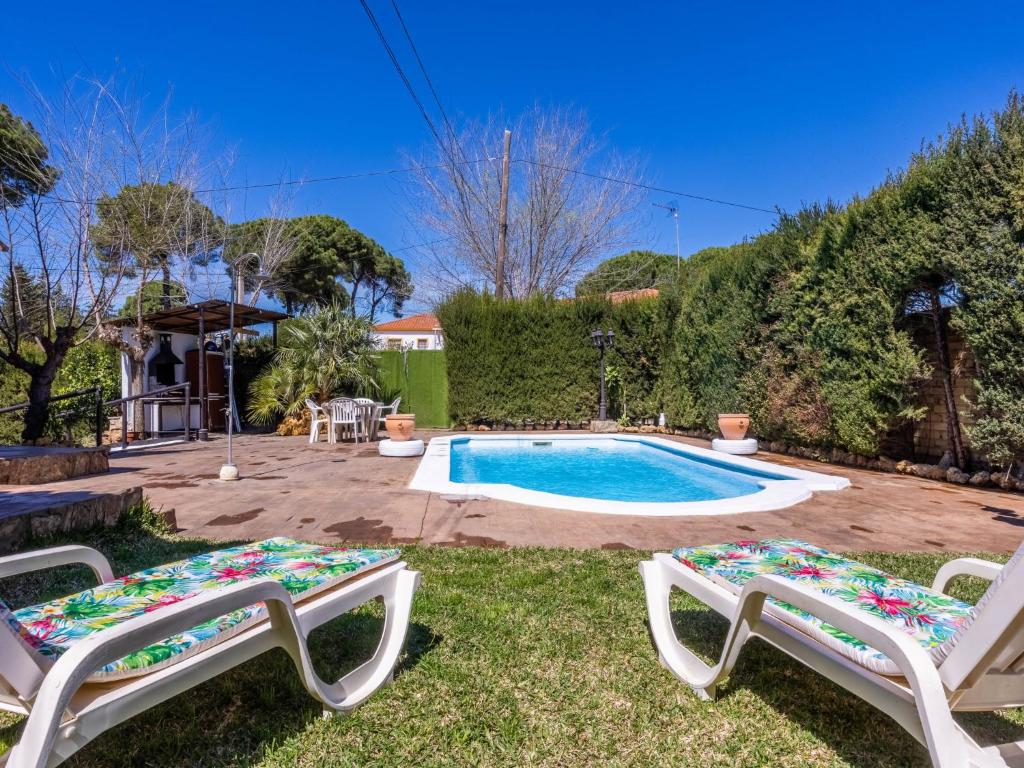 un patio con 2 sillas y una piscina en Holiday Home San Fernando by Interhome en Villanueva del Río y Minas