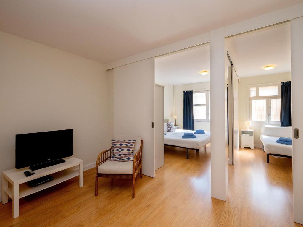 ein Wohnzimmer mit einem TV und ein Zimmer mit einem Bett in der Unterkunft Apartment Sagrada Familia- Rossello by Interhome in Barcelona