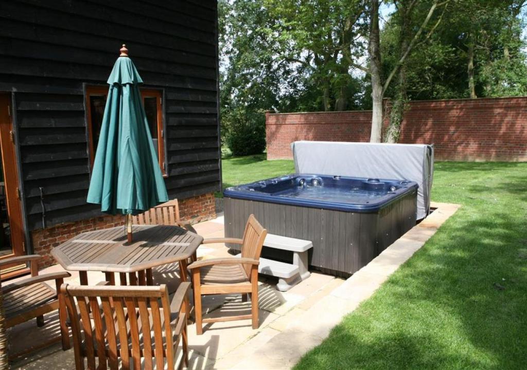 Friston的住宿－Reindeer Cottage Sternfield，一个带桌子和遮阳伞的庭院和一个游泳池