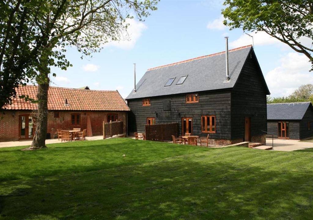 a black barn with tables and chairs in a yard at Red House Barns Sternfield in Friston