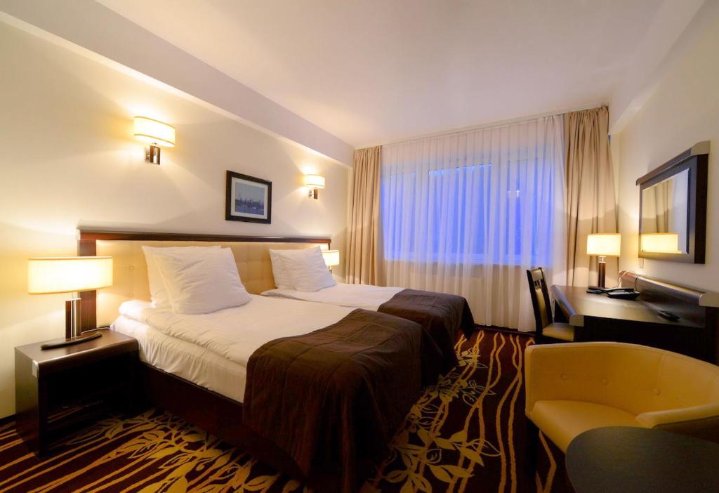 um quarto de hotel com uma cama e uma cadeira em Hotel Business Faltom Gdynia em Rumia