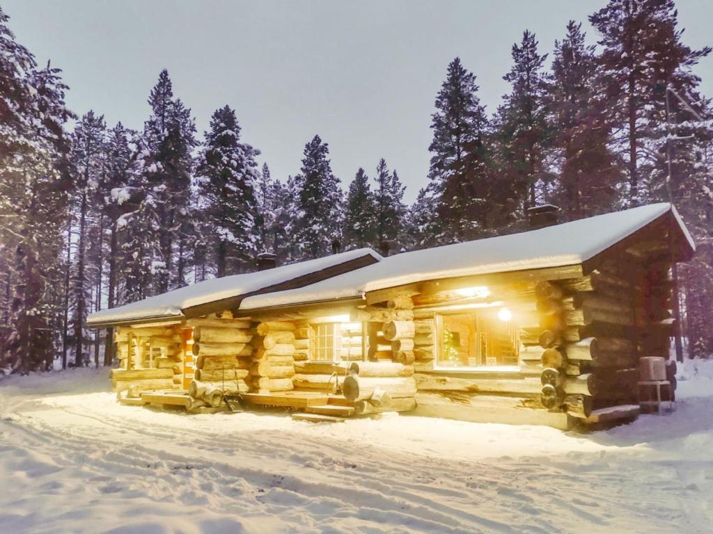een blokhut in de sneeuw met verlichting aan bij Holiday Home Kitkankuru a by Interhome in Kuusamo
