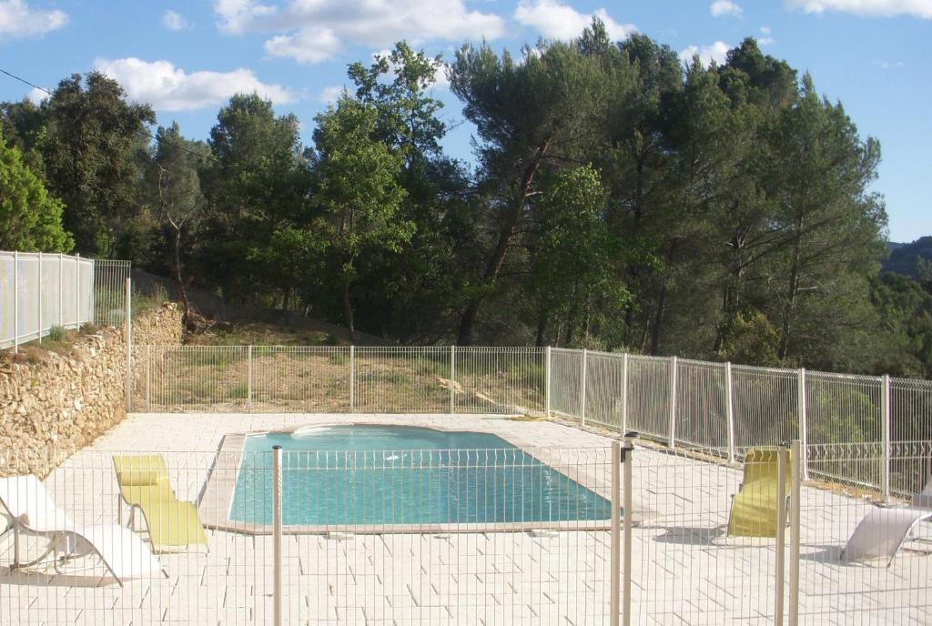 une piscine avec des chaises et une clôture dans l'établissement Le Bastidon des Tilleuls - Gîte de France 3 épis, au Beausset