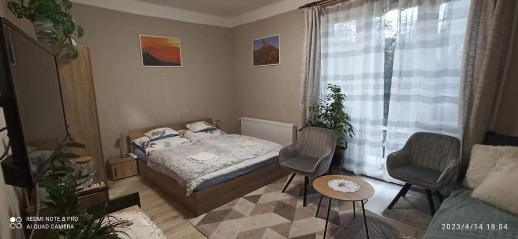 a bedroom with a bed and two chairs and a couch at Karancs Apartman Salgótarján in Salgótarján