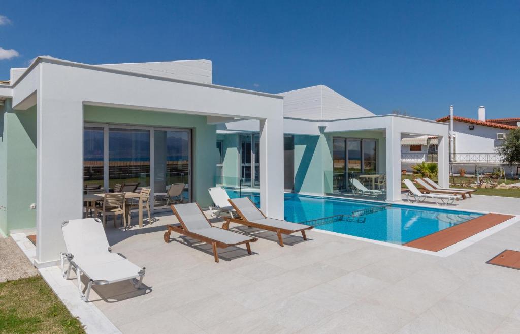 a villa with a swimming pool and lounge chairs at La Villa del Mare - Nafpaktos Beach in Nafpaktos