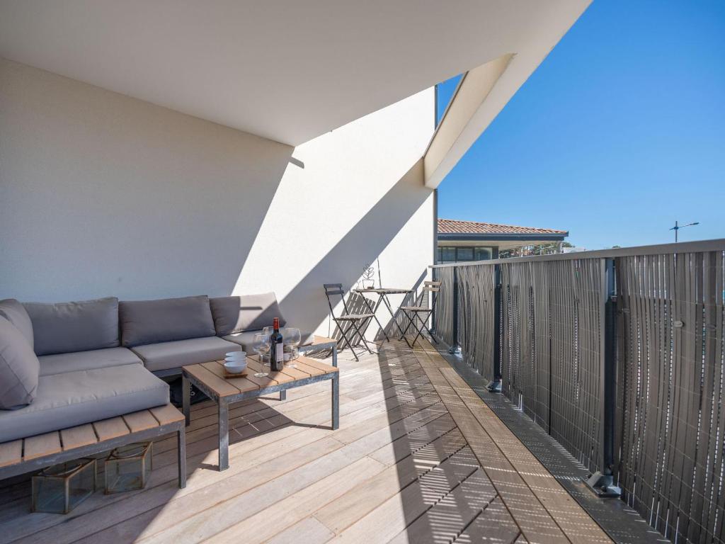 eine Terrasse mit einer Couch und einem Tisch auf einem Balkon in der Unterkunft Apartment Le Rooftop by Interhome in Lacanau-Océan