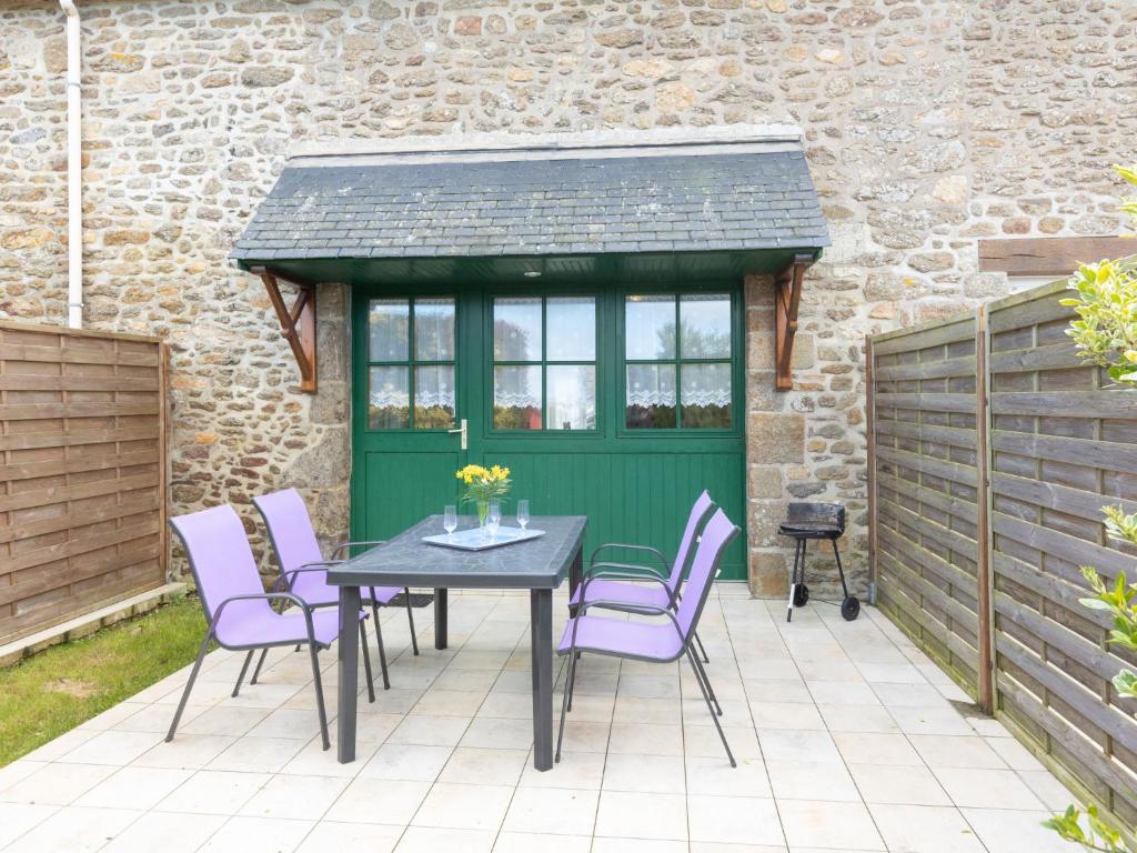 een patio met een tafel en stoelen en een groene deur bij Holiday Home Glaïeuls by Interhome in Saint-Méloir-des-Ondes