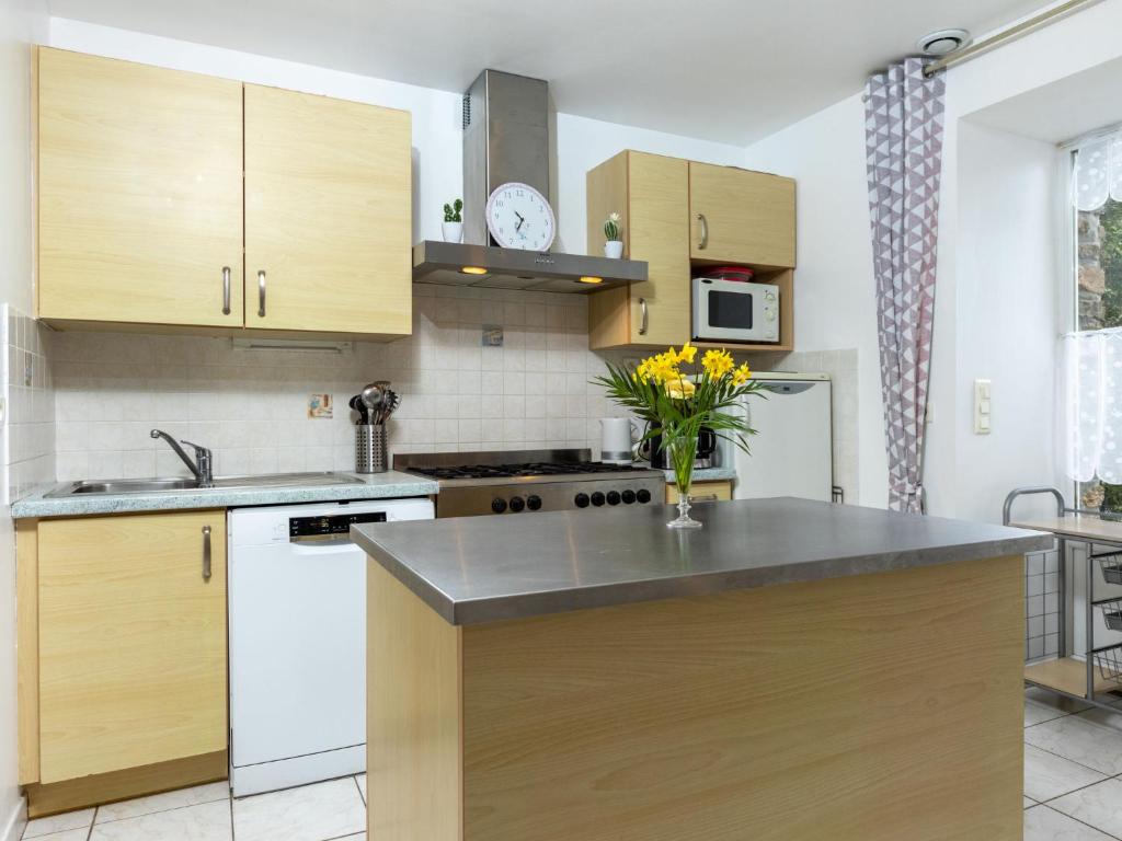 a kitchen with wooden cabinets and a vase of flowers on a counter at Holiday Home Coquelicot by Interhome in Saint-Méloir-des-Ondes