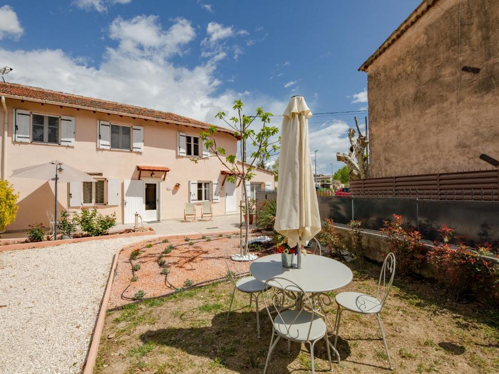 a table with an umbrella and chairs in a yard at Apartment La Bastide de Claude by Interhome in La Roquette-sur-Siagne