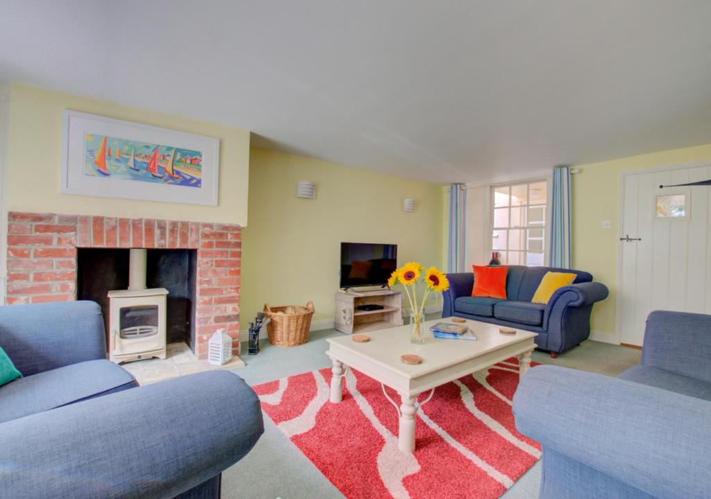 sala de estar con 2 sofás y chimenea en Sandcastle Cottage, en Southwold