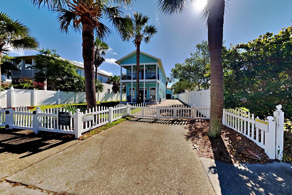 a white fence in front of a house with palm trees at A Mid-Summer's Night Dream in Destin