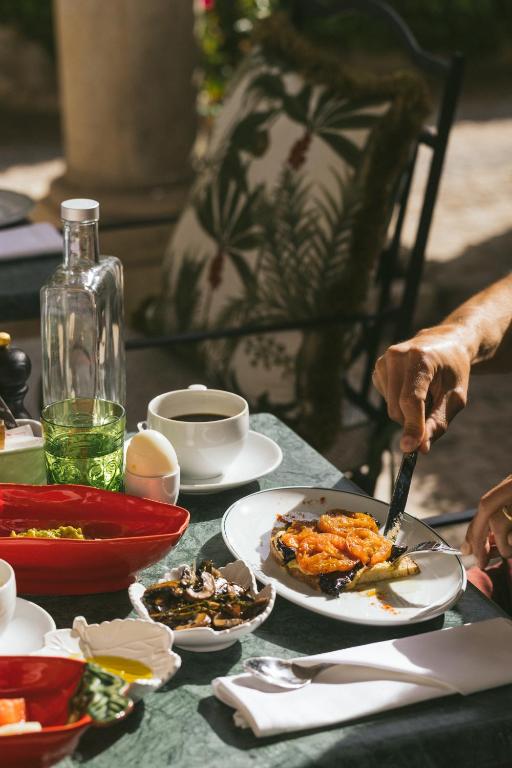a table with plates of food and a person holding a knife at Pergola Boutique Hotel in Cascais