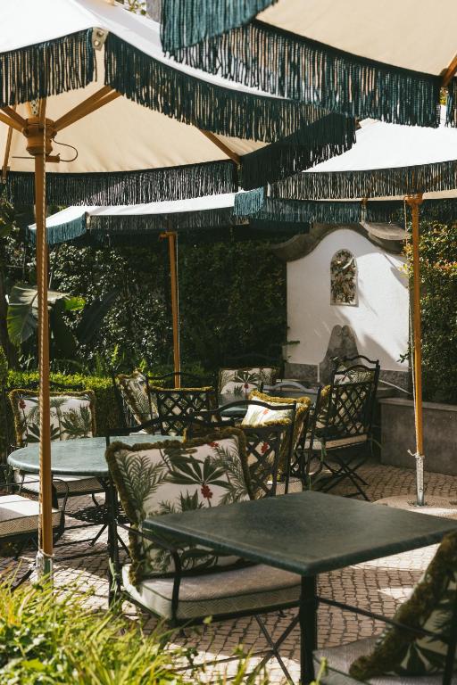 a patio with chairs and tables and umbrellas at Pergola Boutique Hotel in Cascais