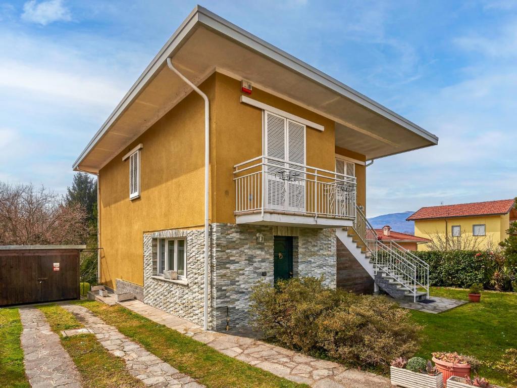 ein gelbes Haus mit einem Balkon und einem Hof in der Unterkunft Apartment Mottarone by Interhome in Laveno-Mombello