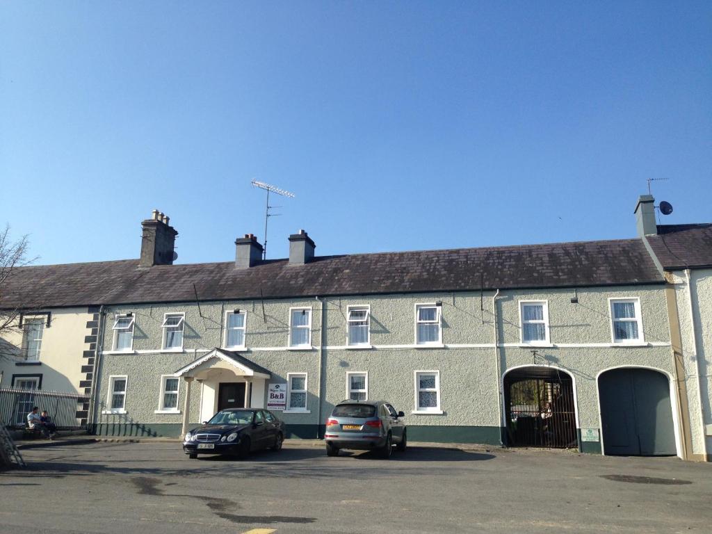 a large building with two cars parked in front of it at Westgate House B&B Strokestown in Strokestown