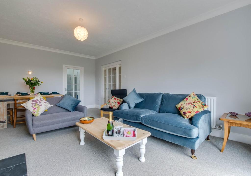 Stonehurst في Aldringham: غرفة معيشة بها كنب ازرق وطاولة قهوة