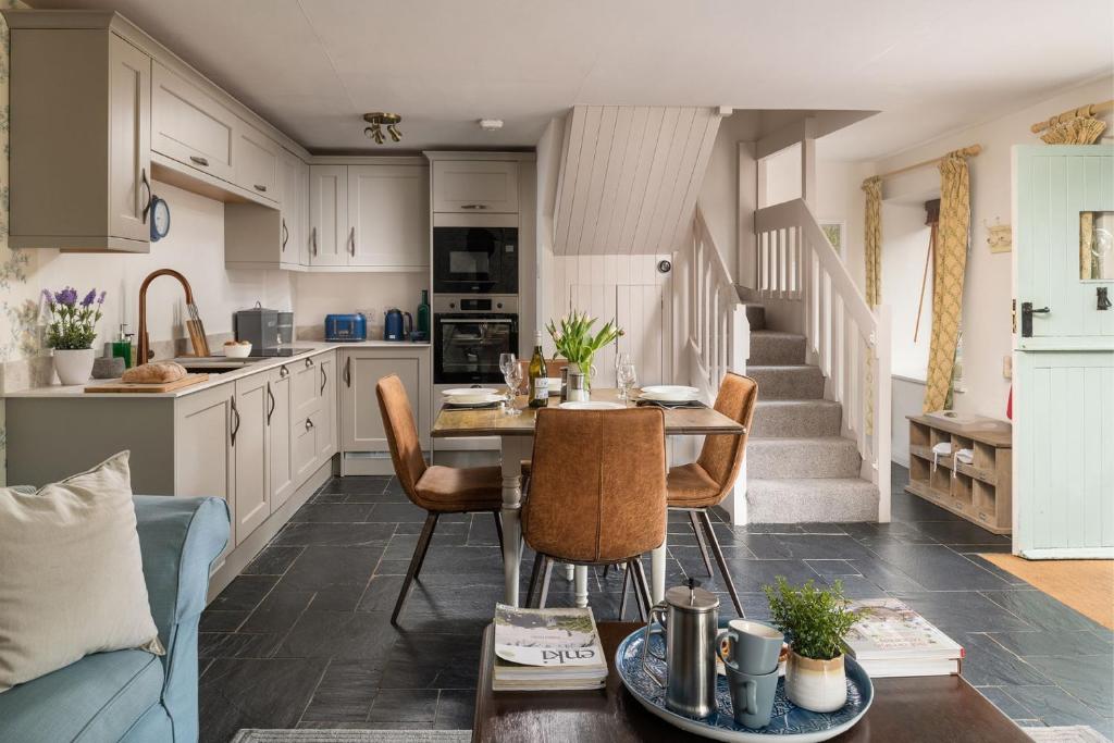 cocina y sala de estar con mesa y sillas en Cuckoo Cottage - Luxury Cottages, en Ilfracombe
