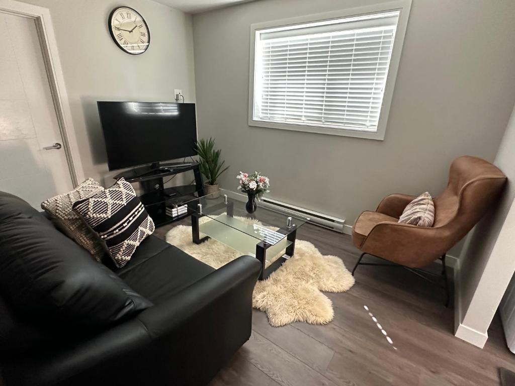 a living room with a couch and a tv and chairs at Cozy BSMT Apt w/2BR+Disney+ Nflx in Saskatoon