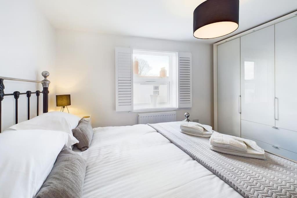 una camera da letto con un grande letto bianco e una finestra di The Snug Central Cosy Good Wi-Fi a Cheltenham