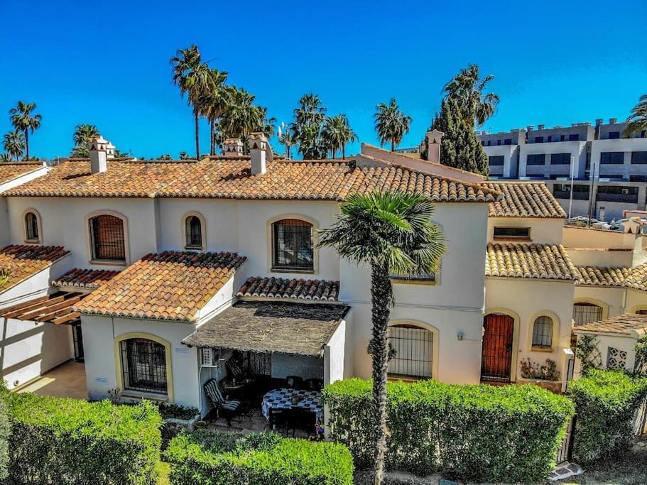 a house with a palm tree in front of it at La Isla Casa Barnaby in Platja de l'Arenal