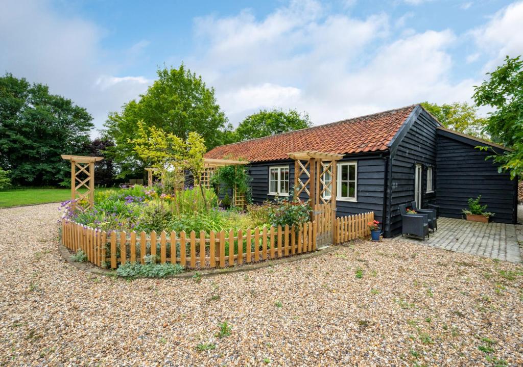 a cottage with a garden in front of it at Sundial and Woodland Lodge in Wilby