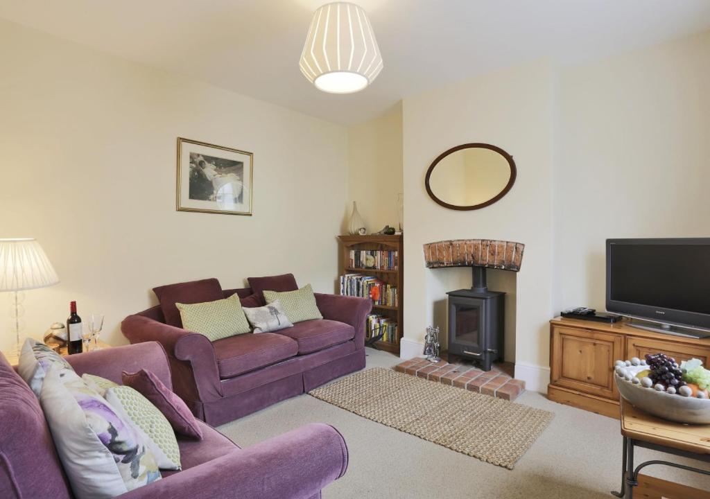 uma sala de estar com dois sofás roxos e uma lareira em The Cornerstone em Southwold
