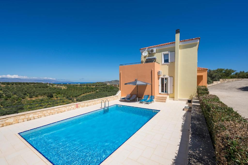 a villa with a swimming pool in front of a house at Olive Tree Villa in Chania