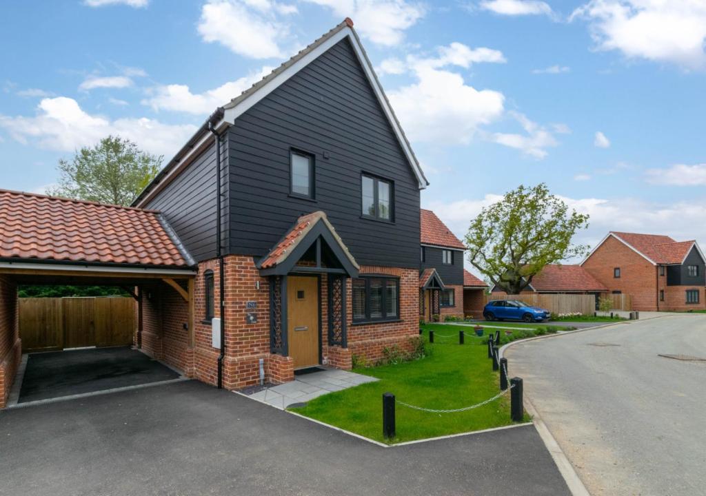 a house with a black roof and a driveway at The Oaks in Laxfield