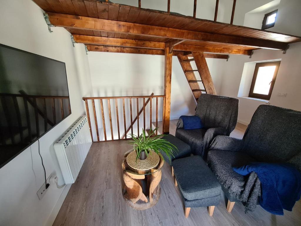 ein Wohnzimmer mit 2 Stühlen und einem TV in der Unterkunft Acogedora y romántica casita en la sierra in Garganta de los Montes