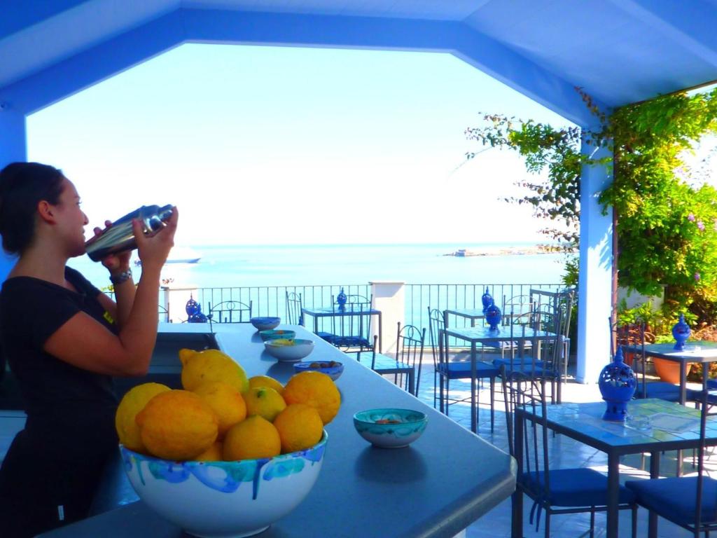 a woman taking a picture of a table with a bowl of oranges at Hotel Palladio in Giardini Naxos