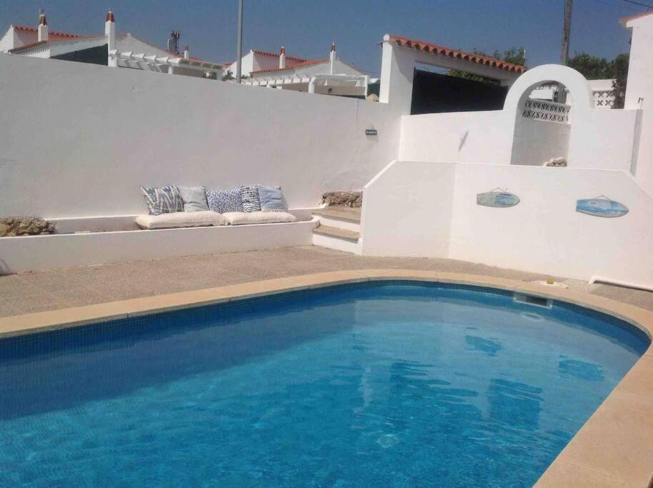 a blue swimming pool in front of a house at Private beautiful house - ( nice swimming Pool) in Cala'n Porter
