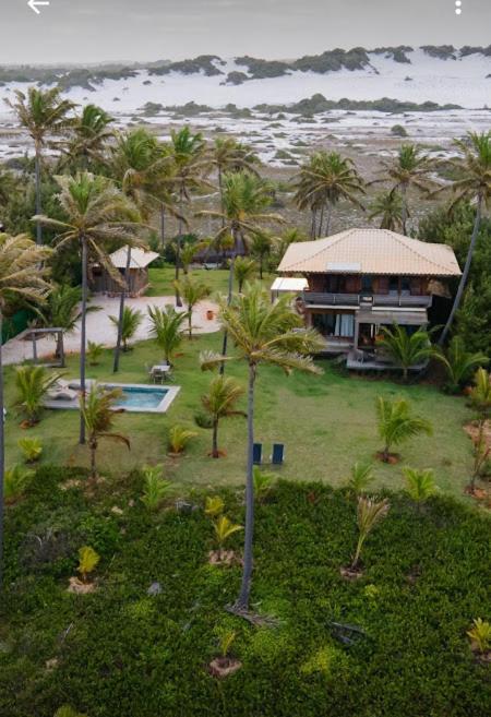 a house with palm trees in front of the ocean at Casa Paraíso Tropical Porto de Sauípe in Canoas