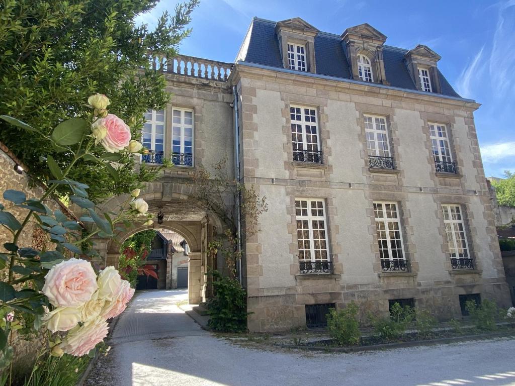 een oud stenen gebouw met een boog en roze rozen bij La Villa Beaupeyrat - Apparthôtels de charme dans bâtisse de caractère in Limoges