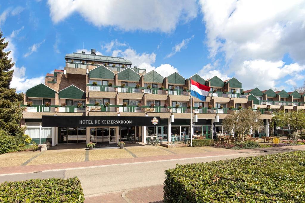 ein Hotel mit einer Flagge vor einem Gebäude in der Unterkunft Bilderberg Hotel De Keizerskroon in Apeldoorn