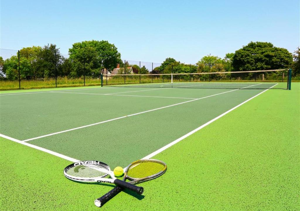 racchetta da tennis e palline su un campo da tennis di West Barn Cottage a Aldringham