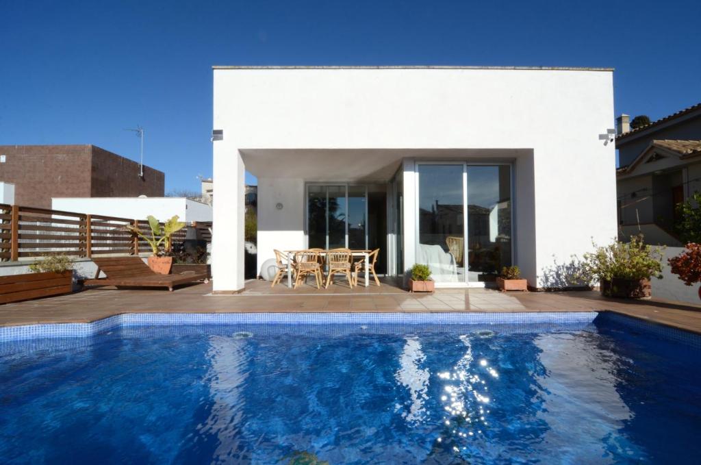 a villa with a swimming pool in front of a house at Ponent in L'Escala